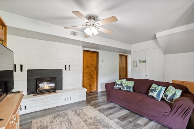 living room featuring wood finished floors, visible vents, a fireplace, and ceiling fan