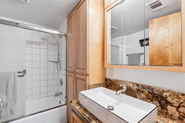 full bathroom with vanity, combined bath / shower with glass door, and visible vents
