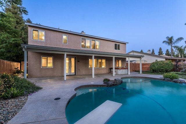 back house at dusk with a jacuzzi and a patio