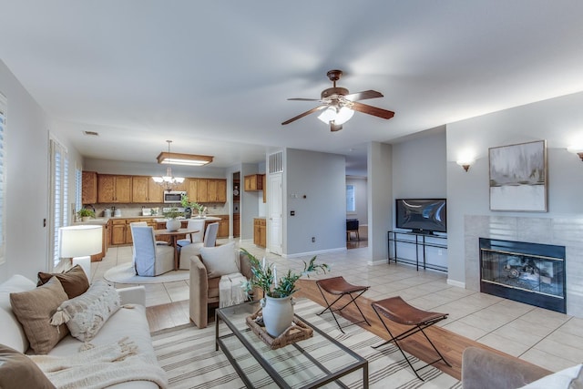 living room featuring light tile patterned floors, ceiling fan with notable chandelier, and a fireplace