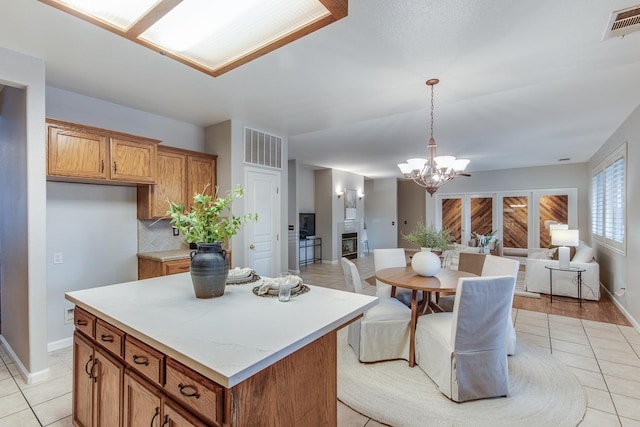 kitchen featuring tasteful backsplash, decorative light fixtures, a center island, a chandelier, and light tile patterned floors