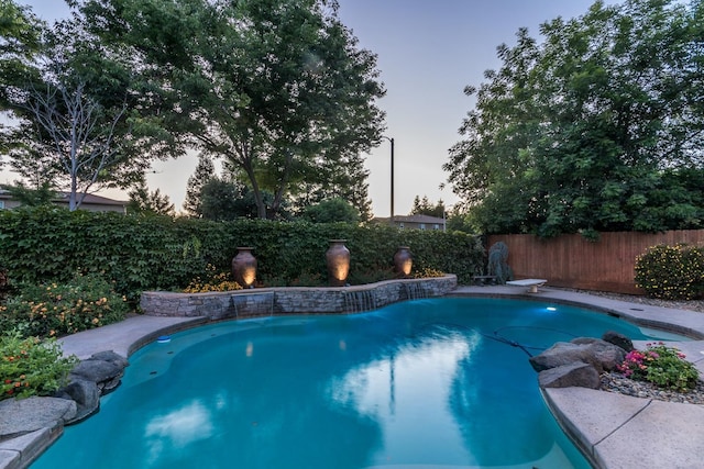 pool at dusk featuring a diving board