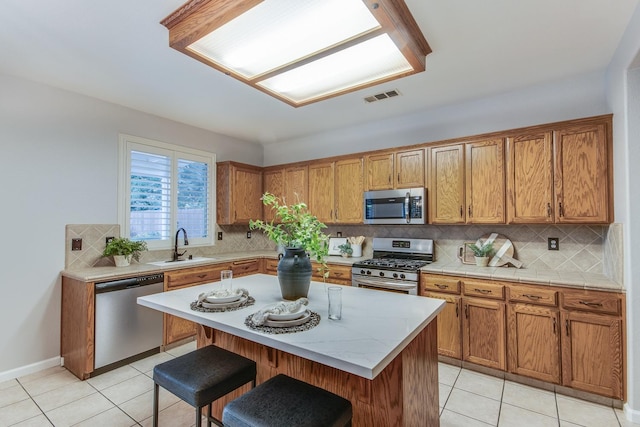 kitchen featuring a kitchen island, tasteful backsplash, sink, a kitchen breakfast bar, and stainless steel appliances