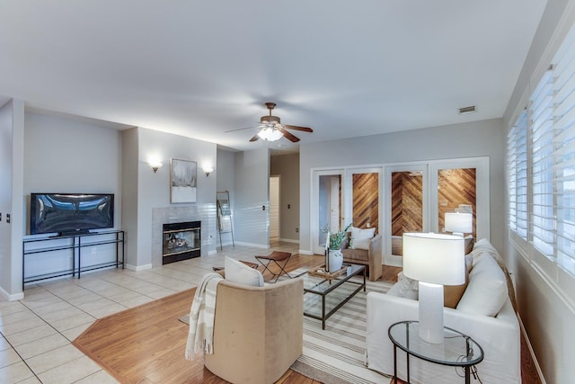 tiled living room with a fireplace and ceiling fan