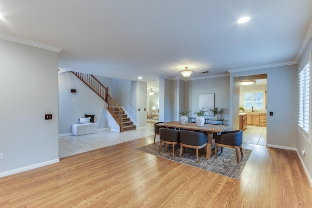 dining space with ornamental molding and light hardwood / wood-style flooring