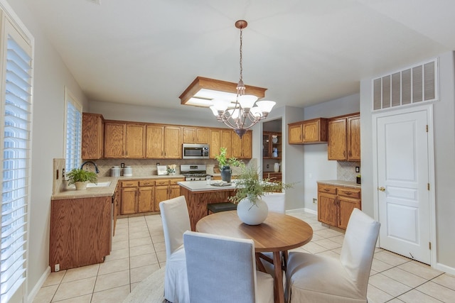 kitchen with hanging light fixtures, a kitchen island, appliances with stainless steel finishes, and light tile patterned floors