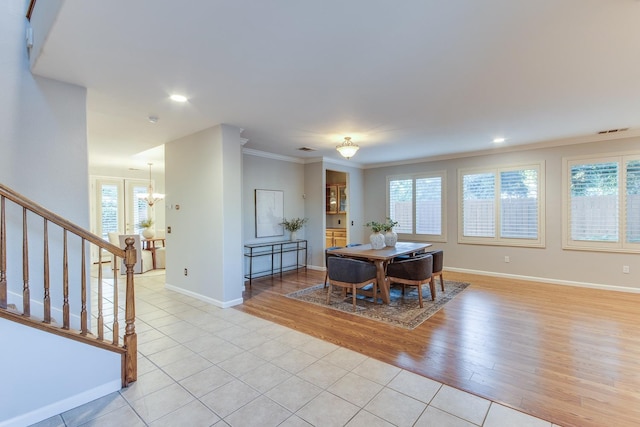 dining space featuring a notable chandelier, light hardwood / wood-style flooring, and ornamental molding