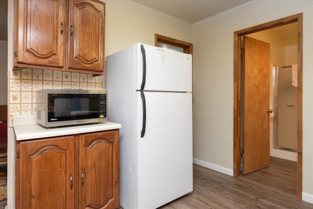 kitchen featuring backsplash, white refrigerator, and hardwood / wood-style floors