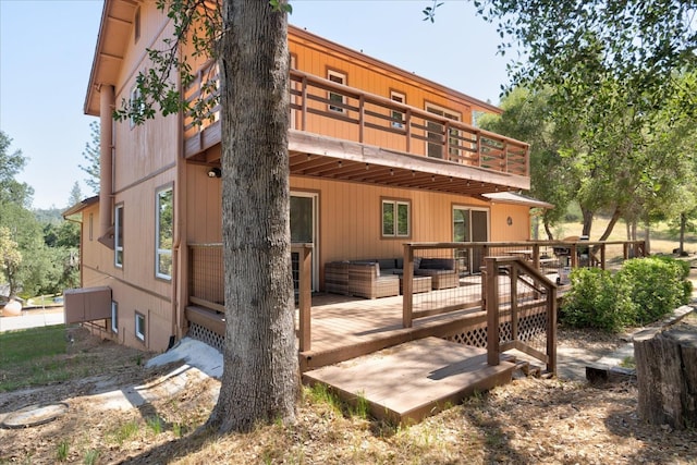 back of property with outdoor lounge area, a deck, and a balcony