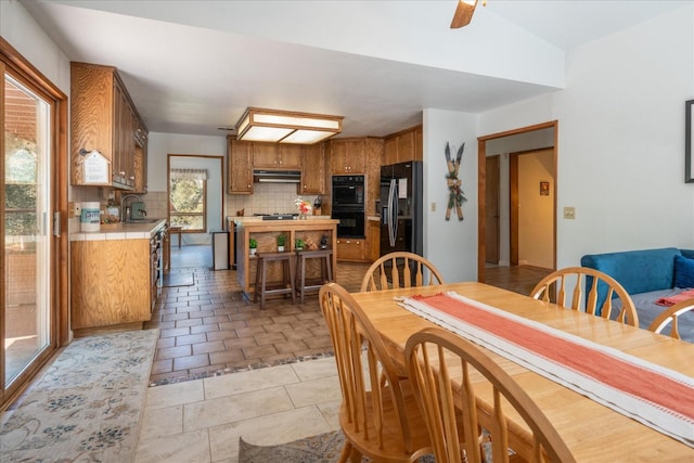 dining room featuring sink, ceiling fan, light tile floors, and vaulted ceiling