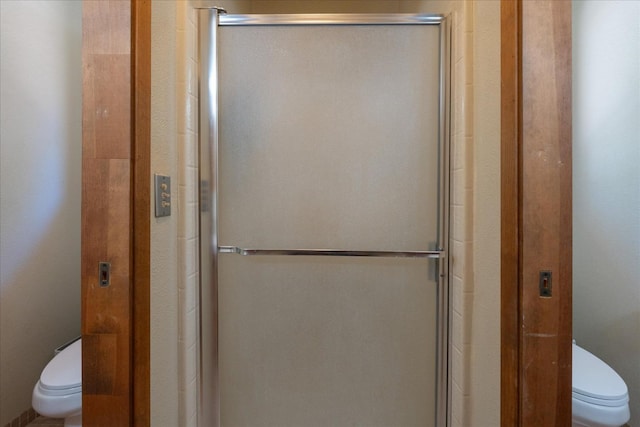 bathroom featuring a shower with shower door and toilet