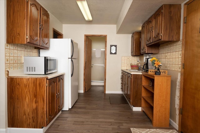 kitchen featuring sink, dark hardwood / wood-style flooring, white refrigerator, and backsplash