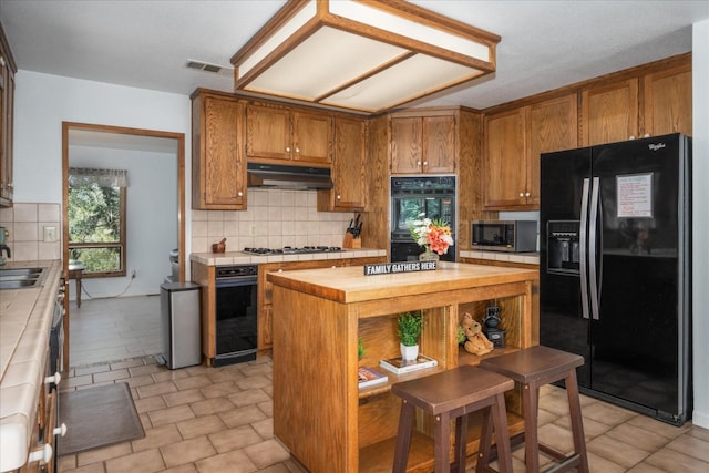 kitchen featuring black appliances, tile countertops, backsplash, sink, and light tile floors