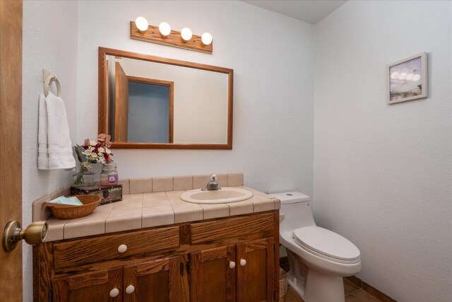 bathroom featuring tile flooring, toilet, and oversized vanity