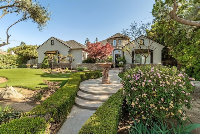 tudor home featuring stone siding, a front lawn, and stucco siding