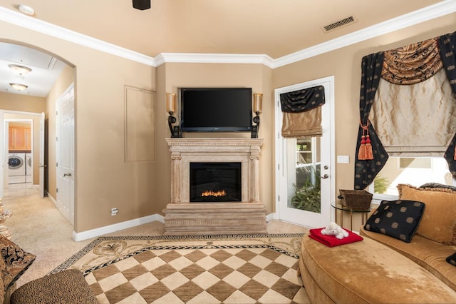 living area featuring baseboards, visible vents, arched walkways, independent washer and dryer, and crown molding