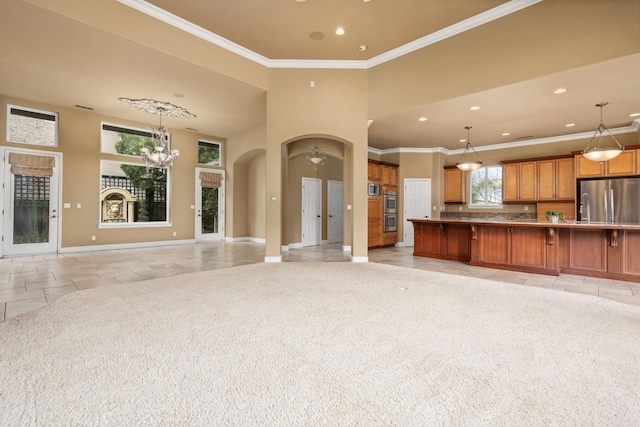 unfurnished living room with arched walkways, light colored carpet, an inviting chandelier, ornamental molding, and baseboards