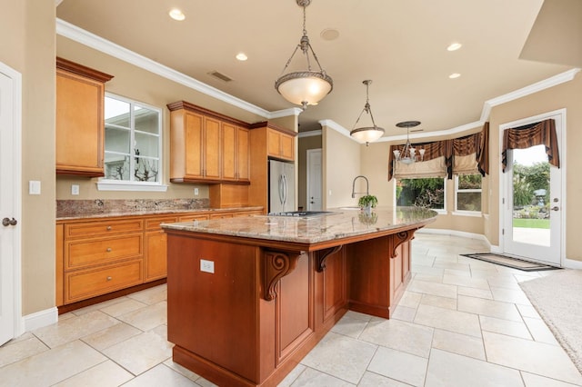 kitchen with visible vents, appliances with stainless steel finishes, ornamental molding, light stone countertops, and a large island with sink