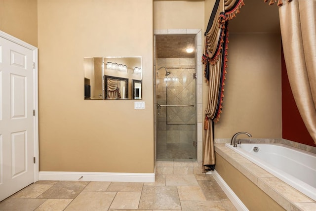 bathroom featuring a stall shower, stone tile flooring, a bath, and baseboards