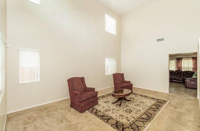 sitting room featuring a high ceiling and light carpet