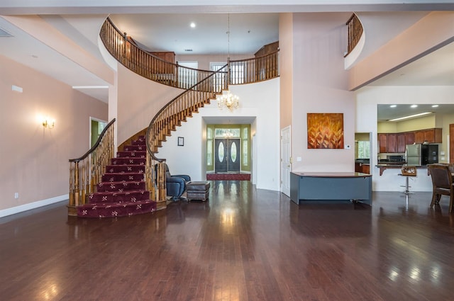 foyer entrance with dark hardwood / wood-style floors, a towering ceiling, and an inviting chandelier