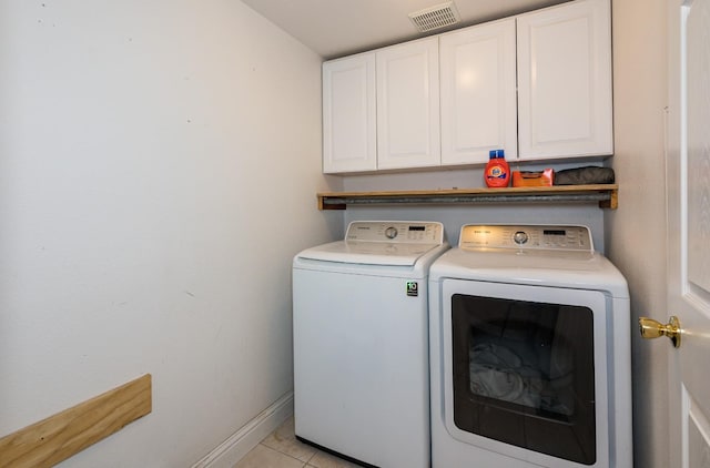 washroom featuring cabinets, washing machine and dryer, and light tile flooring