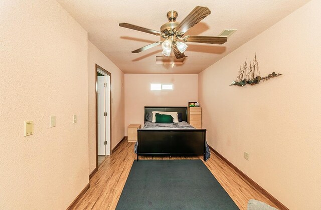 bedroom with ceiling fan, light hardwood / wood-style flooring, and a textured ceiling