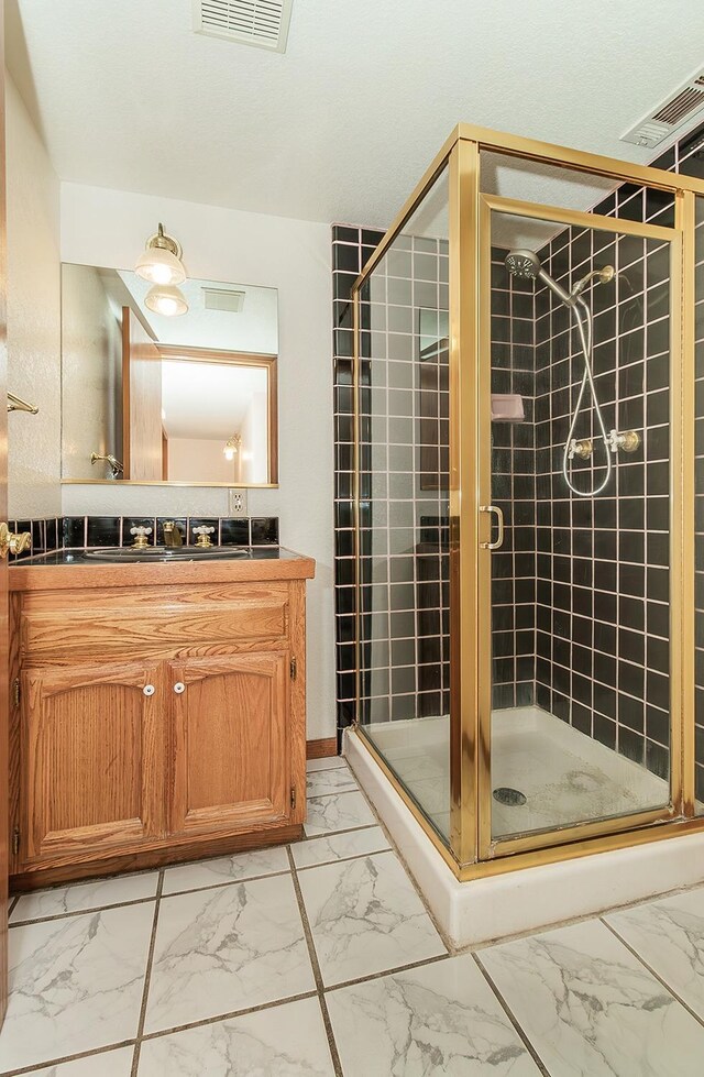 bathroom featuring a shower with door and vanity