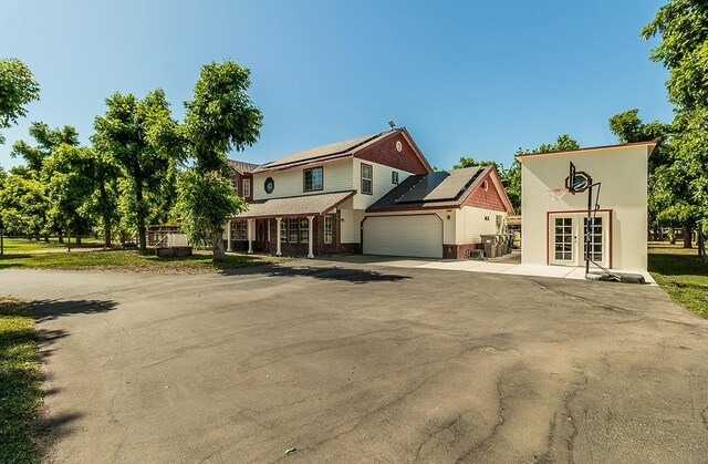 view of front of house with solar panels, a garage, and french doors