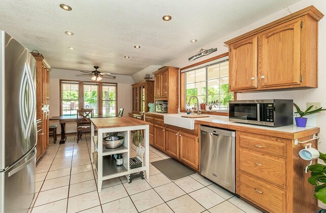 kitchen with appliances with stainless steel finishes, ceiling fan, sink, light tile patterned floors, and butcher block counters