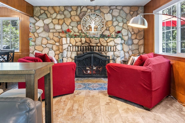 living room with a fireplace, a textured ceiling, and wood walls