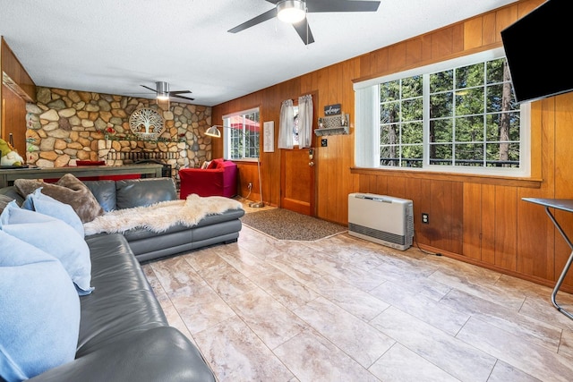 living room with heating unit, wooden walls, a fireplace, and a textured ceiling