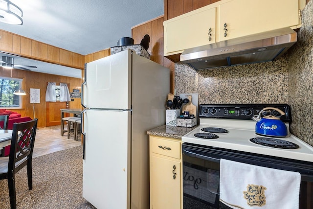 kitchen featuring ceiling fan, range hood, wood walls, white appliances, and hardwood / wood-style flooring