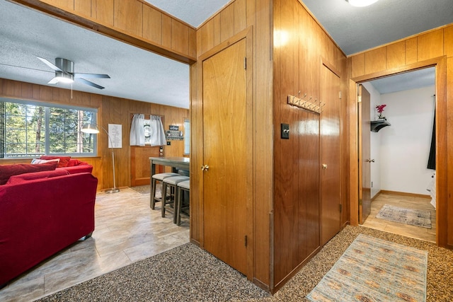 corridor with wooden walls and a textured ceiling