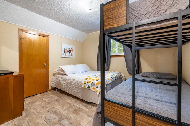 bedroom featuring a textured ceiling and vaulted ceiling