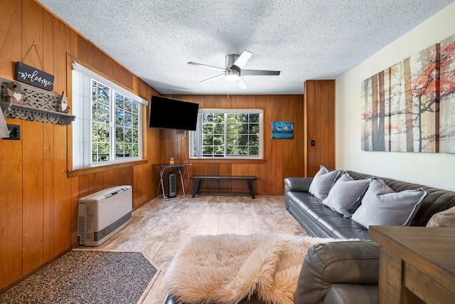 living room with wooden walls, a healthy amount of sunlight, and a textured ceiling