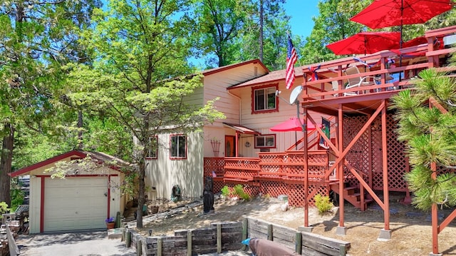 back of house featuring a garage, an outbuilding, and a wooden deck