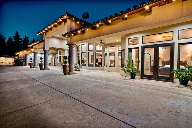 back house at night featuring french doors and a patio