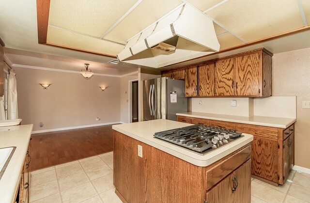 kitchen featuring ventilation hood, light hardwood / wood-style flooring, ornamental molding, a kitchen island, and stainless steel appliances