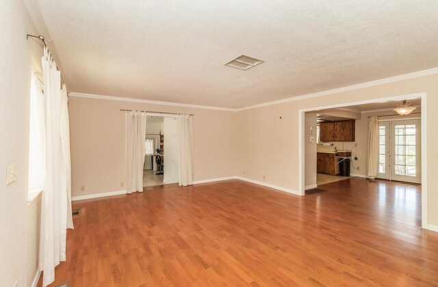 unfurnished living room with wood-type flooring, a textured ceiling, and crown molding