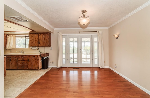 entryway featuring crown molding, plenty of natural light, french doors, and light wood-type flooring