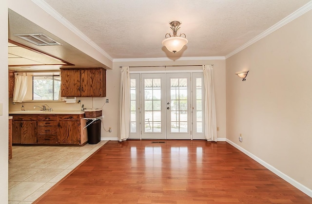 doorway with french doors, sink, crown molding, a textured ceiling, and light wood-type flooring