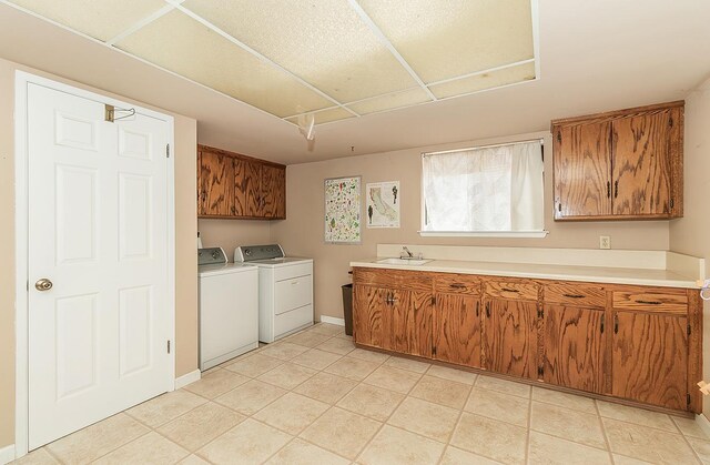 clothes washing area featuring cabinets, light tile patterned floors, sink, and washing machine and dryer