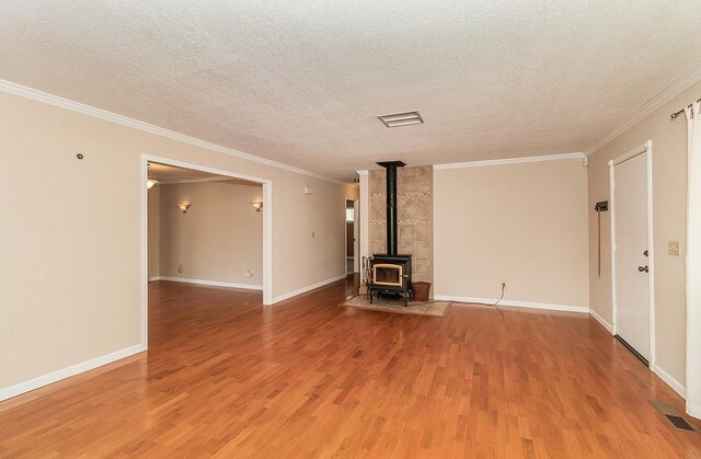 unfurnished living room featuring hardwood / wood-style floors, a textured ceiling, a wood stove, and ornamental molding