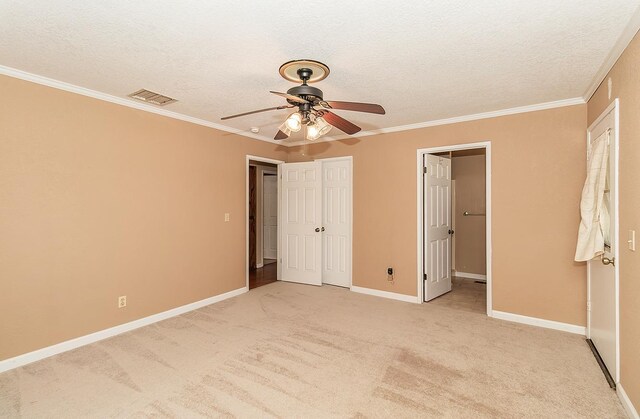 unfurnished bedroom with a textured ceiling, light colored carpet, ceiling fan, and ornamental molding