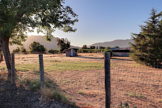 view of yard featuring a mountain view, a rural view, and a storage shed