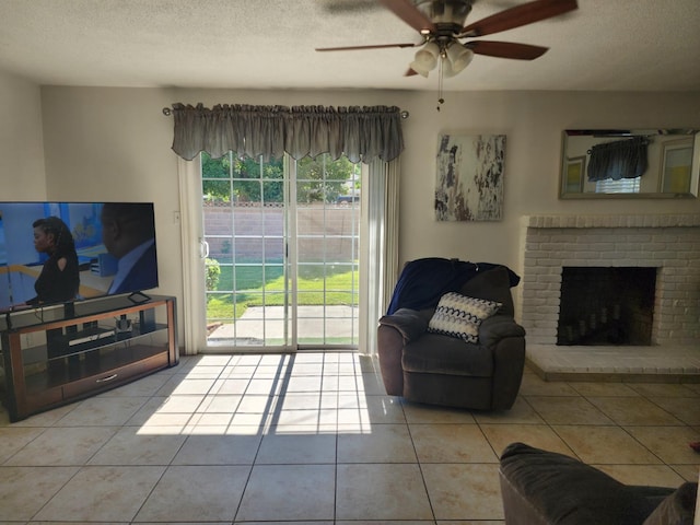 tiled living room featuring ceiling fan, a fireplace, and a textured ceiling