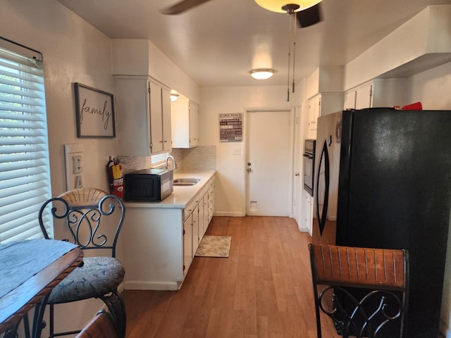 kitchen featuring sink, white cabinetry, tasteful backsplash, light hardwood / wood-style flooring, and black appliances