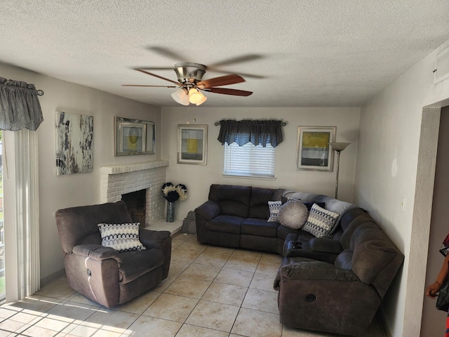 tiled living room with ceiling fan, a textured ceiling, and a fireplace