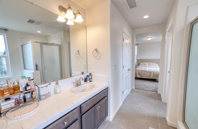 bathroom with a shower with shower door, vanity with extensive cabinet space, and tile flooring